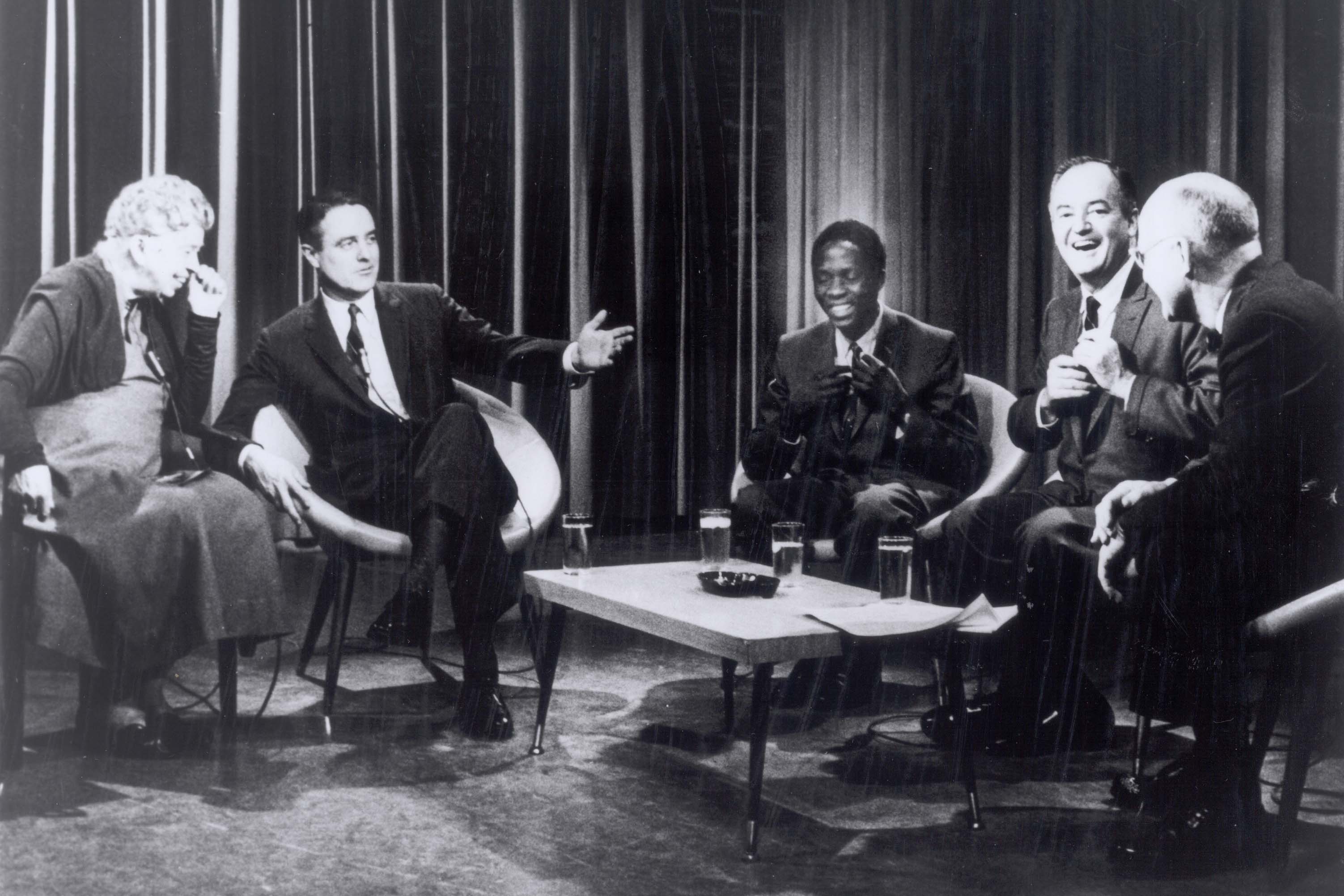 Eleanor Roosevelt sitting and laughing with a group of men in chairs
